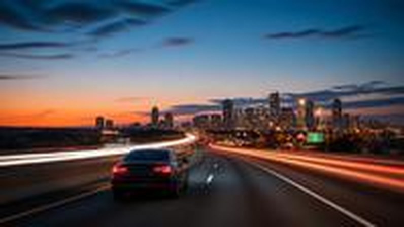 Highway at dusk toward a city skyline